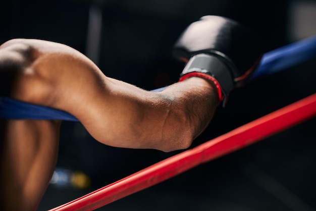 Sportgevecht en hand van een boksman die in de hoek van een boksring rust tijdens een oefening of training van een tentoonstellingswedstrijd Motivatie fitness en training bokser ontspannen en moe na het vechten