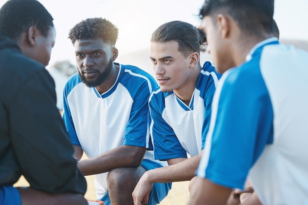 Sportgroep en voetbalteam in gesprek met hun coach voor een wedstrijdtraining of toernooi Fitnessteamwerk en mannelijke voetballer of atleten die een spelstrategie plannen tijdens de training op een veld