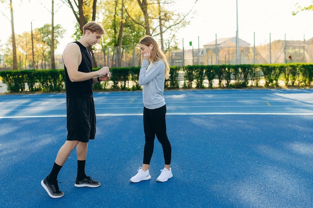 Sportief jong stel in het stadion met elkaar in gesprek De man en het meisje bereiden zich voor om samen te trainen Het concept van een gezonde levensstijl