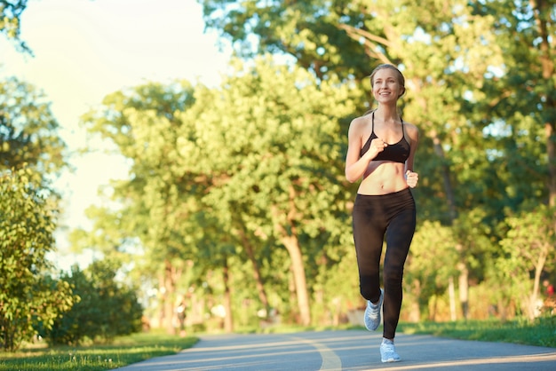 Sportief meisje dat langs renbaan in het stadspark loopt.