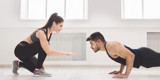 Sportief meisje helpt haar vriendje push-ups te doen in studio, panorama, kopieer ruimte