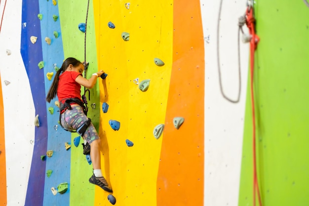 Sportief meisje kunstmatige rots klimmen op praktische muur in de sportschool