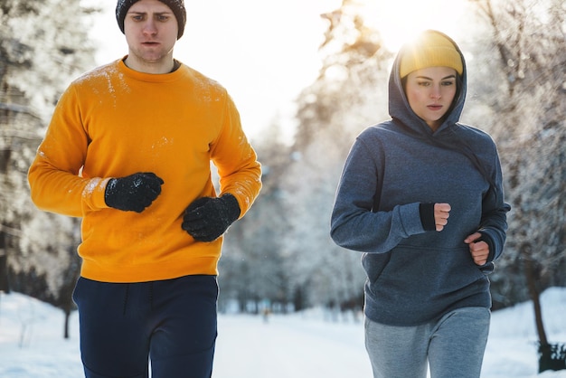 Sportief paar tijdens de winterjoggen in het besneeuwde stadspark