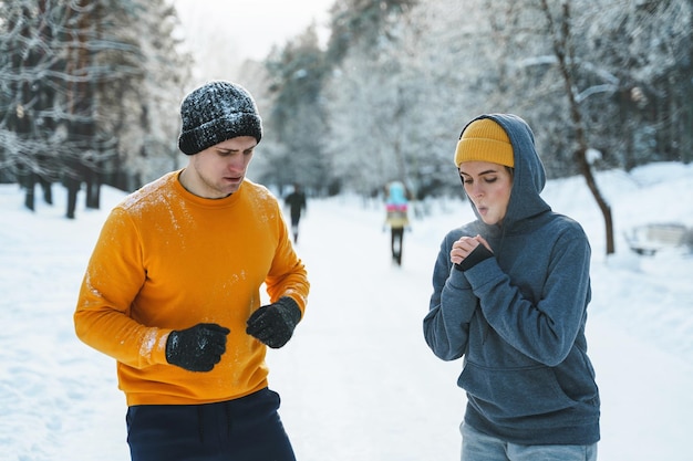 Sportief paar tijdens de winterjoggen in het besneeuwde stadspark