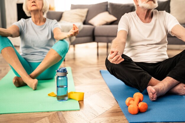 Sportief senior koppel dat thuis fitness- en ontspanningsoefeningen doet - Ouderen trainen om gezond en fit te blijven