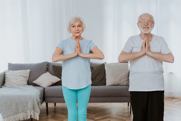 Sportief senior koppel dat thuis fitness- en ontspanningsoefeningen doet - Ouderen trainen om gezond en fit te blijven