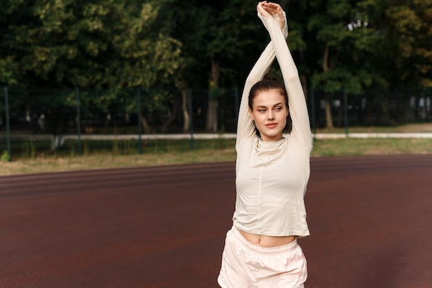 Sportief vrouwelijk mooi model gaat buiten sporten en kijkt naar de camera