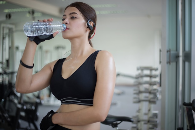 Sportief vrouwenazië drinkwater na oefeningen in de gymnastiek. Fitness - concept van gezond