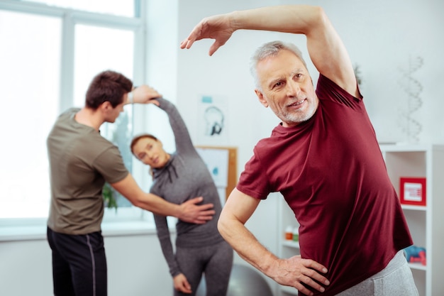 Sportieve activiteit. Aardige knappe man die lacht terwijl hij een lichaamsbeweging doet