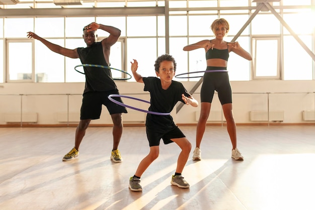 sportieve afro-amerikaanse familie in sportuniform draait hoelahoep en doet oefeningen in de sportschool