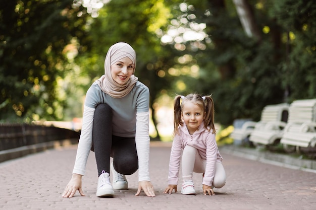 Sportieve Arabische moeder en haar schattige dochter op de atletiekbaan maken zich klaar om te gaan rennen