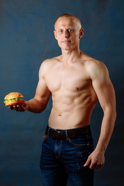 Sportieve atleet met hamburger. Ongezonde voeding of sport, levensstijlkeuze. Junk food concept