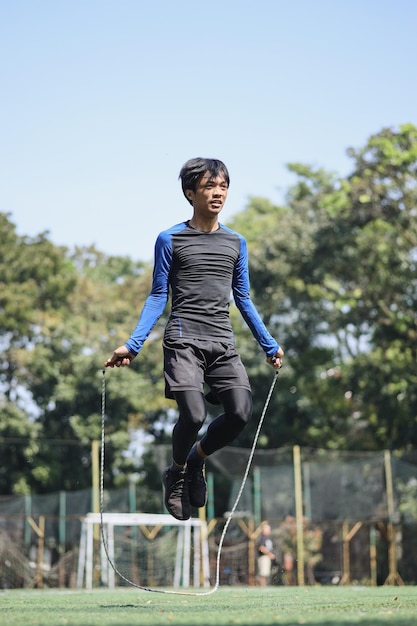 Sportieve atletiek jonge man in sport uniform oefenen met touwtjespringen op sportschool park achtergrond