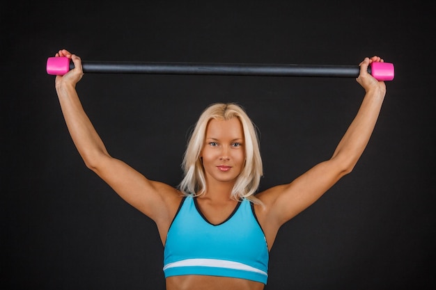 Sportieve blonde fitness vrouw doet oefeningen met expander.