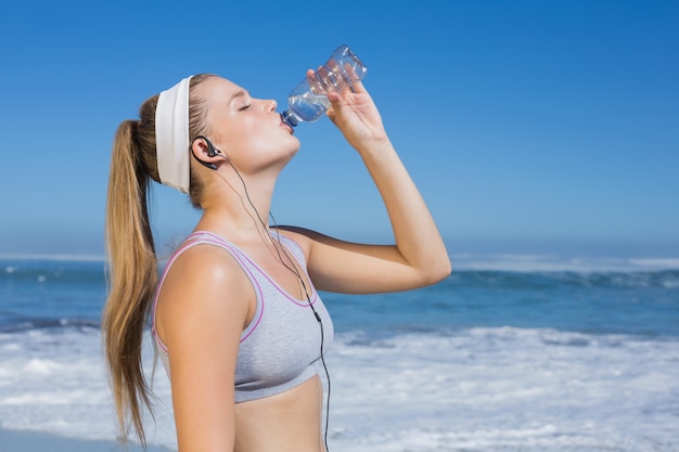 Sportieve blonde op het strand drinkwater