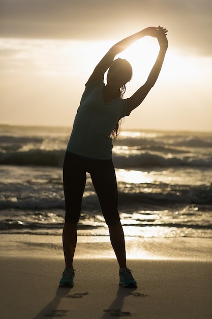 Sportieve brunette die zich uitstrekt op het strand