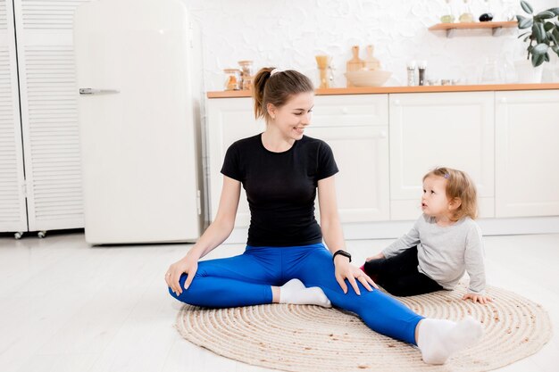 Sportieve brunette moeder en dochter zittend op de keuken rekken en lachend interieur