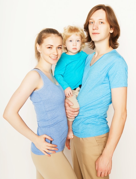 Sportieve en gelukkige familie - moeder, vader en zoontje poseren over witte ruimte