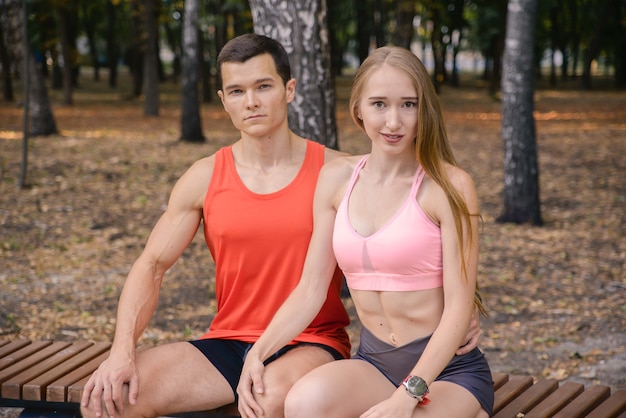Sportieve jonge paar man en vrouw die verschillende oefeningen buitenshuis doen
