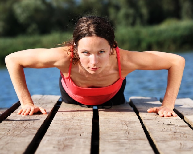 Sportieve jonge vrouw die push-ups buitenshuis doet. De opname is gemaakt met een gepolariseerd filter