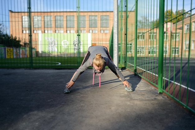 Sportieve jonge vrouw die zich uitstrekt in het park