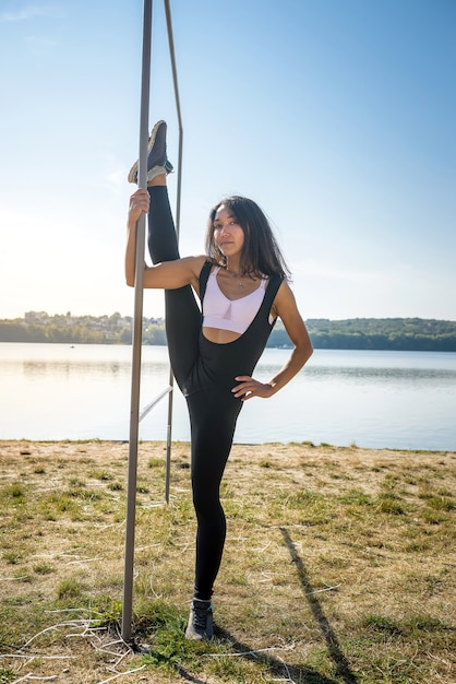 Sportieve jonge vrouw fitness oefeningen doen in de buurt van het meer overdag. Gezond levensstijlconcept