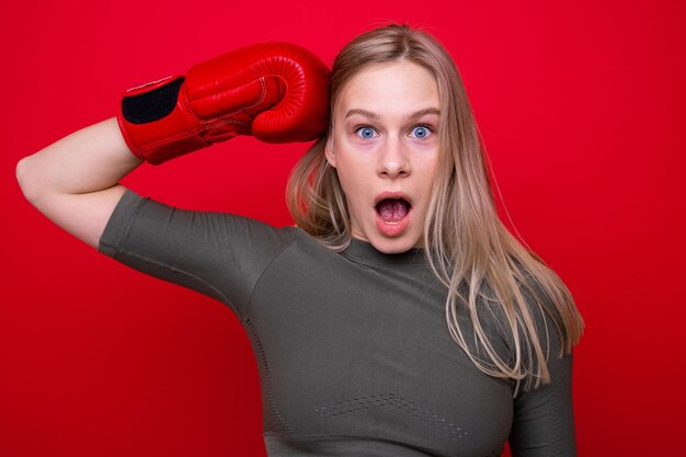 Sportieve jonge vrouw in rode bokshandschoenen die pret hebben