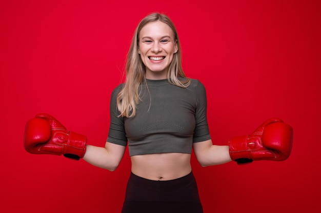 Sportieve jonge vrouw in rode bokshandschoenen die pret hebben