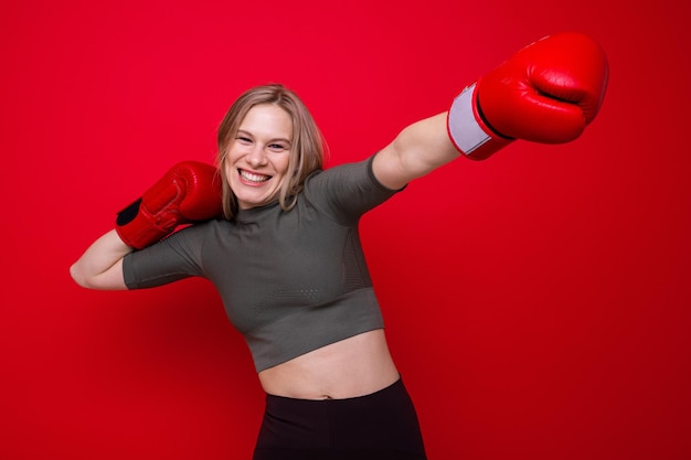 Sportieve jonge vrouw in rode bokshandschoenen is aan het dollen