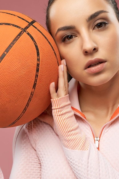 Sportieve jonge vrouw met oranje basketbalbal