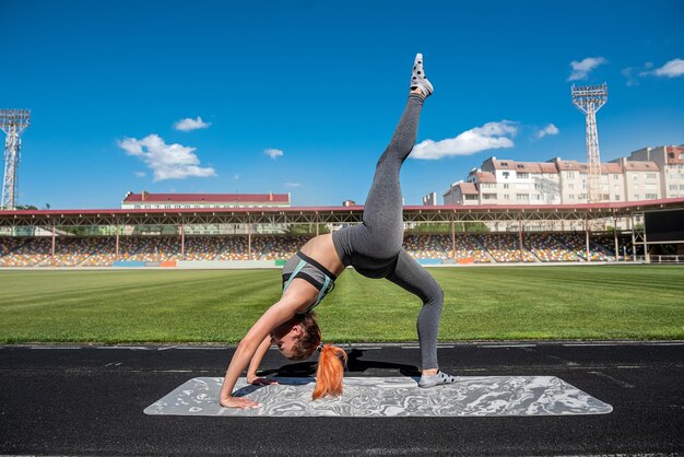 Sportieve jonge vrouwelijke atleet die de benen uitrekt in de gezonde levensstijl van het sity-stadion