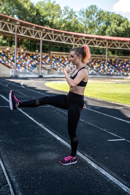 Sportieve jonge vrouwelijke atleet die de benen uitstrekt in het sity-stadion
