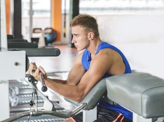 sportieve jongeman die zijn biceps uitoefent in de sportschool