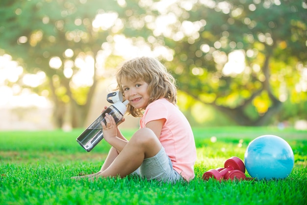 Sportieve jongen in park drinkwater kinderen sport kind fitness gezondheid en energie oefeningen met halter