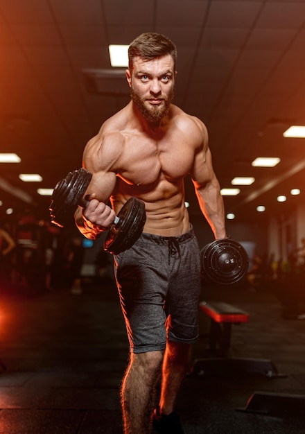 Sportieve knappe man aan het werk in de sportschool met naakte torso. jonge bodybuilder met naakte gespierde binnen werken.