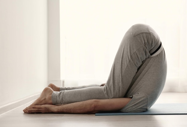 Sportieve man die binnen yoga beoefent