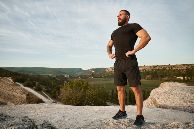 Sportieve man die op een heuvel op het platteland staat