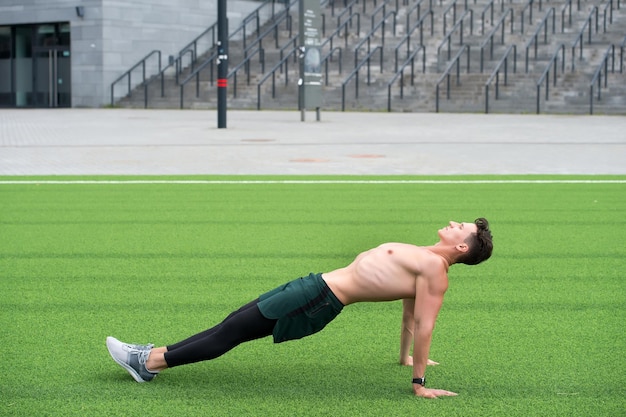 Sportieve man die plankoefening maakt. man in omgekeerde plankoefening. Yoga fitness man lichaam uitrekken in opwaartse plank pose. omgekeerde planking oefening buiten op parkgras doen. totale lichaamskracht.