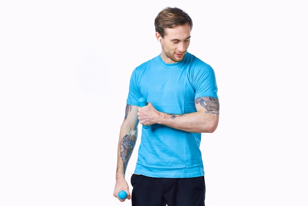 Sportieve man met een tatoeage op zijn arm in een blauw T-shirt en spieren bodybuilding fitness foto van hoge kwaliteit
