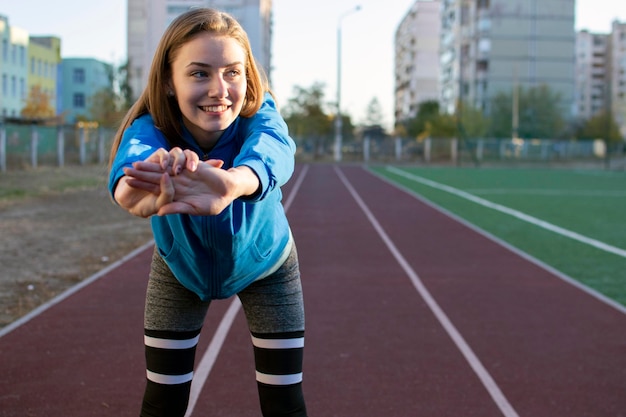 Sportieve meid die opwarmt op een turnster van een loopbandvrouw die buiten traint in de ruimte voor het kopiëren van sportkleding