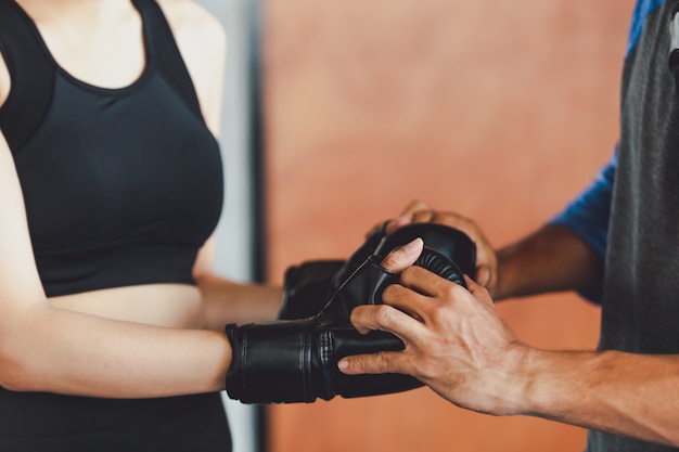 Sportieve meisjes mooie vrouw met de achter bokshandschoenen die bij de gymnastiek opleiden