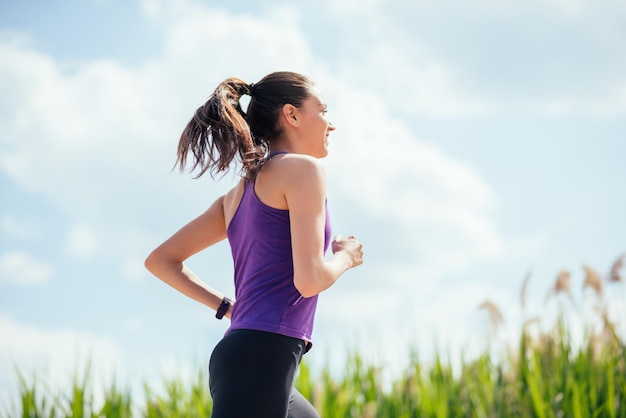 Sportieve mooie vrouw die in park op aardachtergrond loopt Zonnige dag harde training Sport