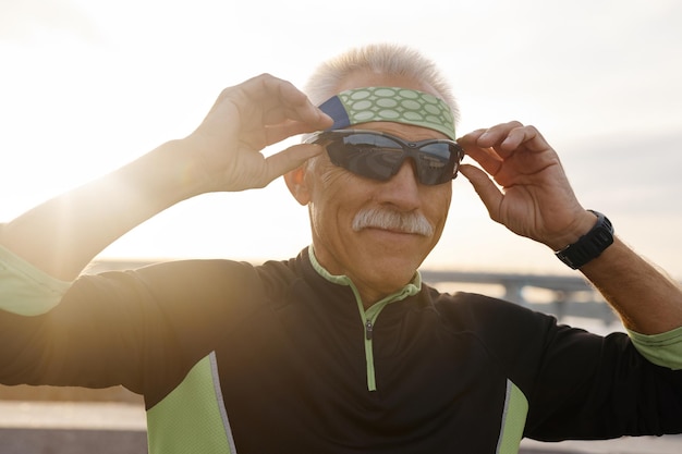 Foto sportieve senior man die een zonnebril opzet
