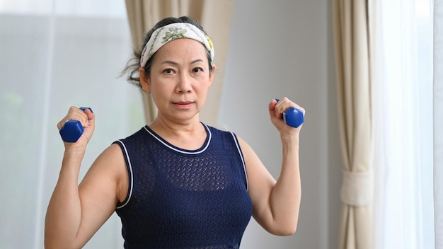 Sportieve senior vrouw trainen met halters thuis Pensioen gezonde levensstijl concept