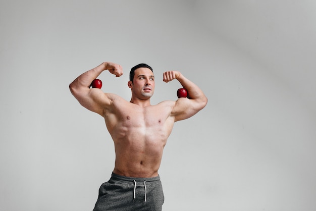 Sportieve sexy man poseren op een witte achtergrond met heldere vruchten. eetpatroon. gezond dieet.