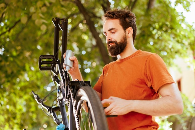 Sportieve toegewijde man die gespecialiseerd smeermiddel gebruikt om zijn fietsketting te smeren. De afbeelding toont een blanke man die vakkundig het kettingblad van zijn fiets smeert voor een naadloze fietservaring.