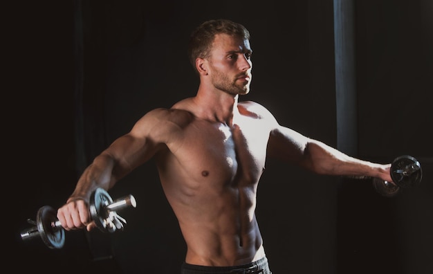 Sportieve torso man met dumbbells gespierde man doet crossfit jonge man aan het trainen in de atletische studio