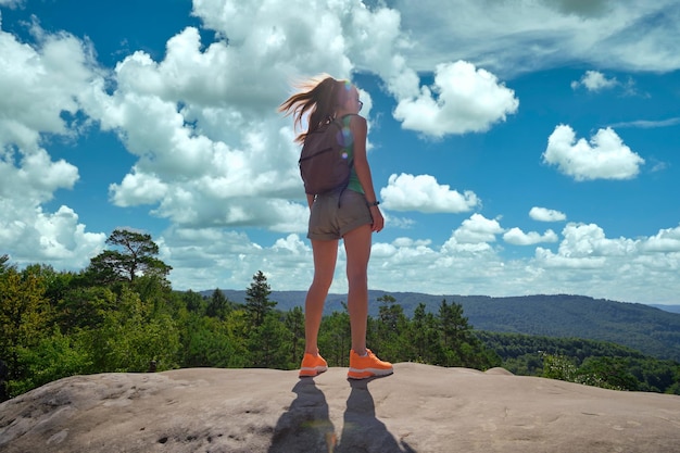 Sportieve vrouw die alleen op een heuvelpad staat Vrouwelijke wandelaar die geniet van het uitzicht op de zomernatuur vanaf een rotsachtige klif op een wildernispad Actief levensstijlconcept