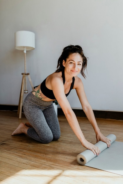 Sportieve vrouw die een yogamat rolt