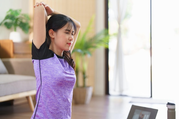 Sportieve vrouw die elleboog en schouder uitrekt tot ontspanning na thuis yoga te hebben gedaan